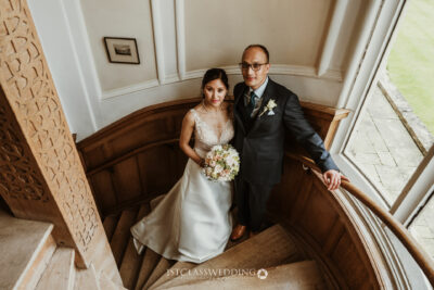 Bride and groom on staircase in elegant venue.