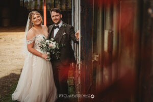Bride and groom posing by rustic train carriage.