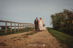 Couple walking on rural path at countryside wedding.
