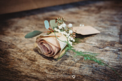Elegant wedding boutonniere on rustic wooden surface.
