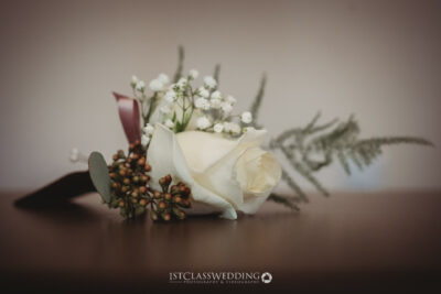 Elegant white rose wedding boutonniere on table