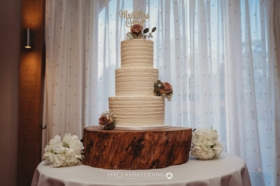 Elegant wedding cake with roses on wooden stand.
