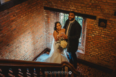 Couple on staircase in historic venue with champagne.