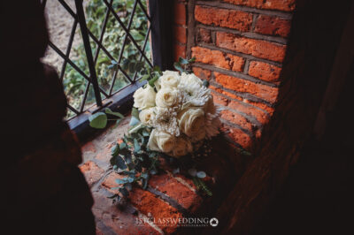 Elegant bridal bouquet on brick windowsill.