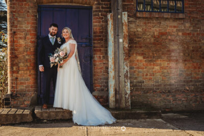Bride and groom posing by rustic blue door.