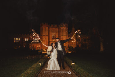 Couple with sparklers by castle at night wedding