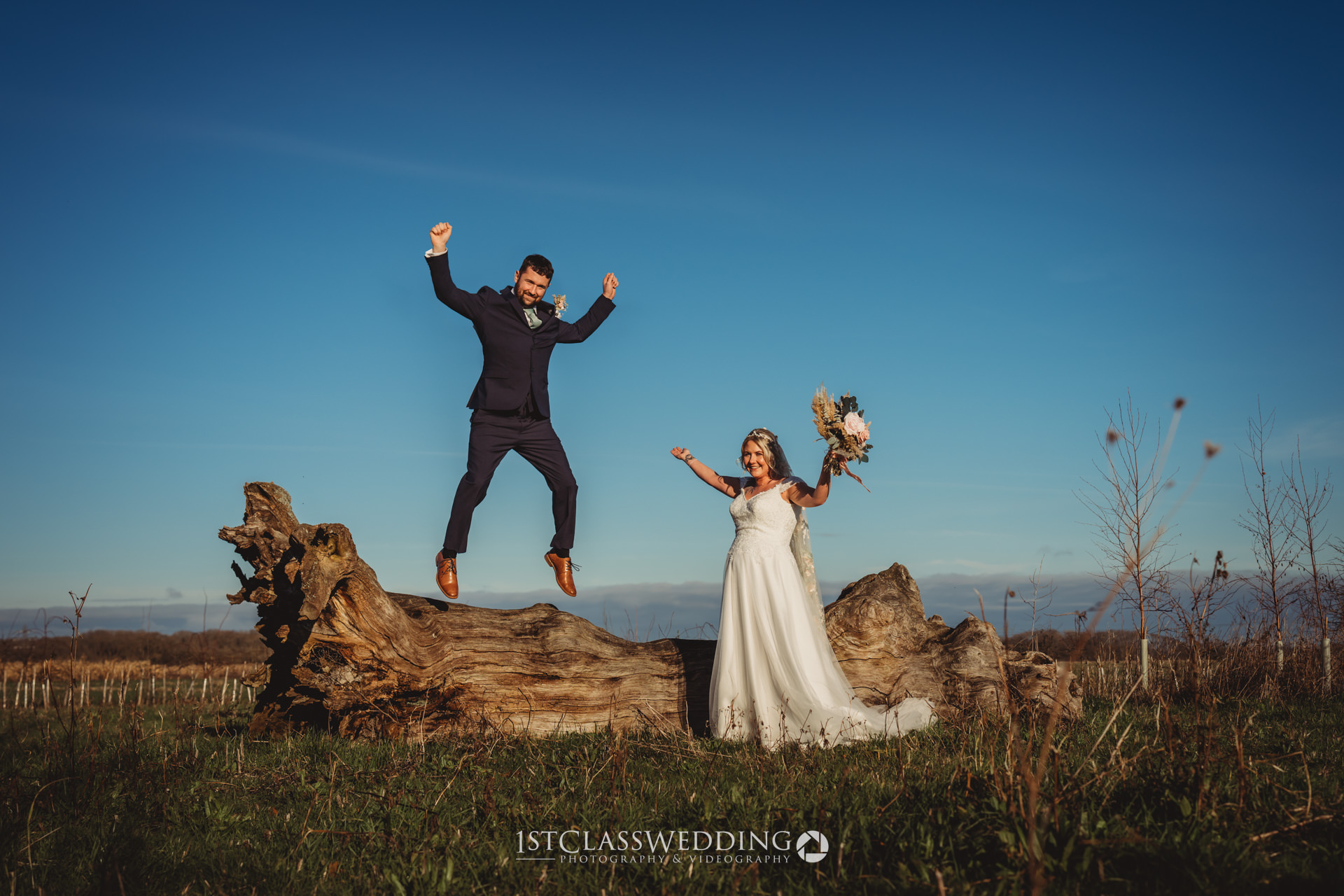 Joyful wedding couple jumping and celebrating outdoors.