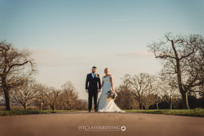 Couple on pathway in scenic countryside wedding.