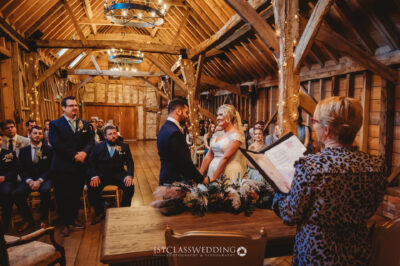 Couple exchanging vows in rustic barn wedding ceremony.