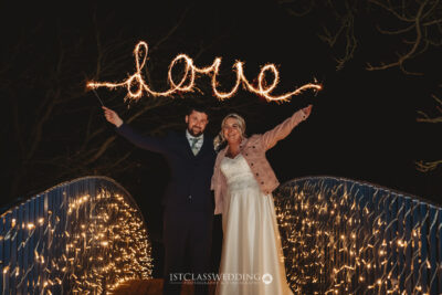 Couple with sparkler writing 'love' at night wedding.