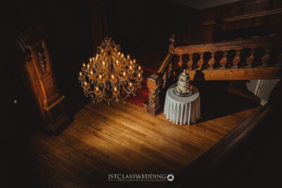 Elegant wedding cake under chandelier in historic venue.