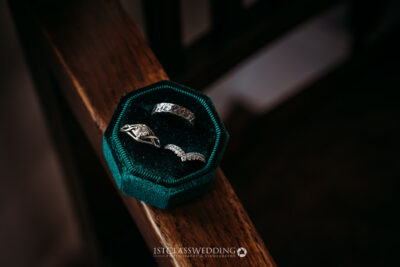 Wedding rings in emerald box on wooden surface.