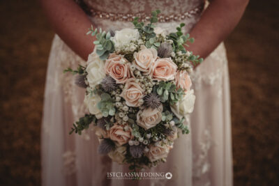Bride holding peach rose wedding bouquet.