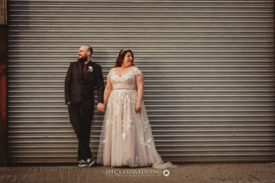 Couple in wedding attire by metal shutter.