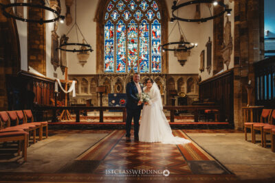 Couple at wedding in historical church with stained glass.