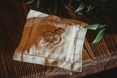 Wedding rings on elegant napkin, wooden table setting.