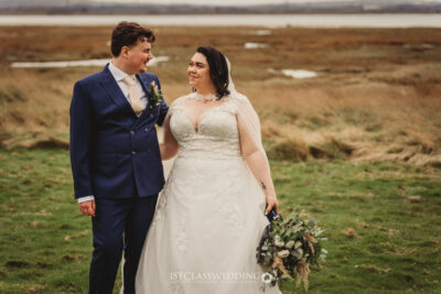 Wedding couple posing in field, joyful moment.