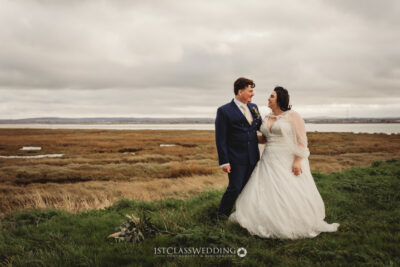 Couple in wedding attire by marshland.