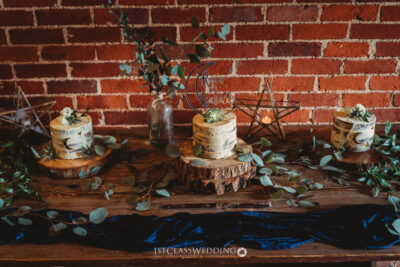 Rustic wedding cakes on wooden stands with eucalyptus decor.