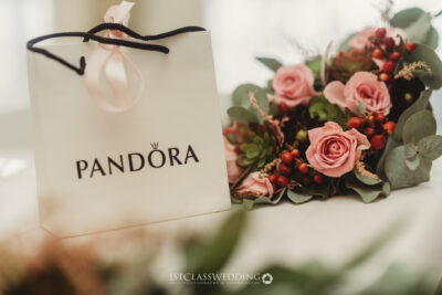Pandora bag and elegant floral arrangement on table.