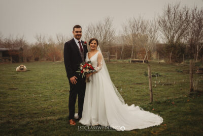 Bride and groom posing outdoors at countryside wedding.