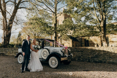 Couple with vintage wedding car by church