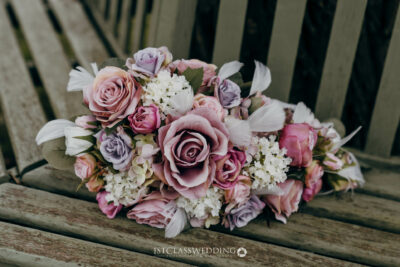 Bridal bouquet with pink and lilac roses on bench