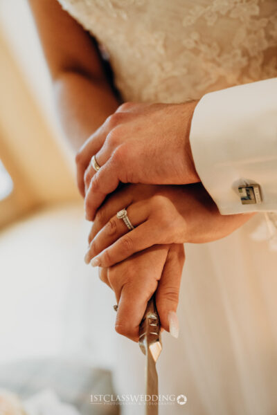 Close-up of wedding couple holding hands with rings.