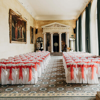 Elegant wedding ceremony venue with white chairs and red bows.