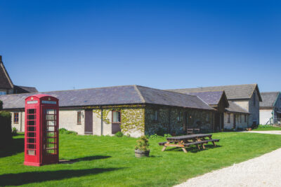 Traditional British red phone box by stone cottages.