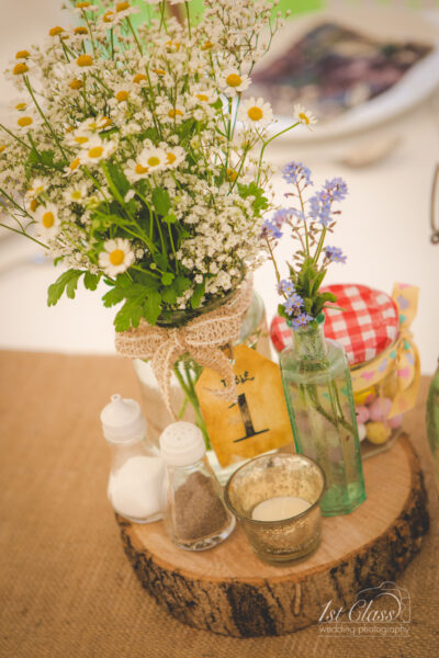 Rustic wedding table centerpiece with wildflowers and wood slice.