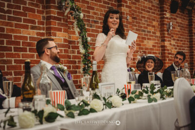 Bride giving speech at wedding reception.