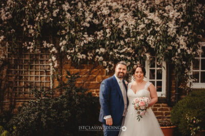 Bride and groom smiling in front of floral wall at Crockwell Farm