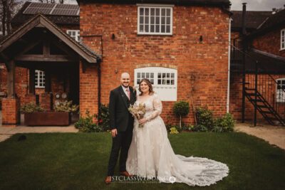 Bride and groom posing at rustic brick venue Donnigton Park Farmhouse.
