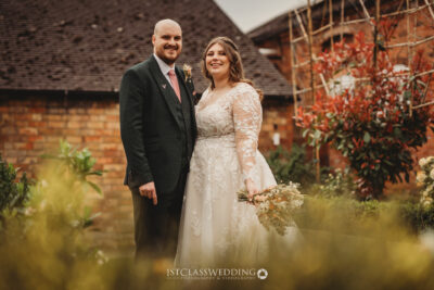 Bride and groom smiling in garden setting.