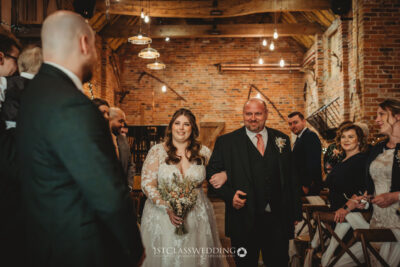 Bride walking down aisle with father in rustic Donnigton Park Farmhouse venue.
