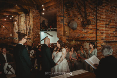 Couple exchanging vows in rustic Donnigton Park Farmhouse wedding venue.