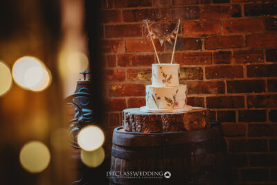 Elegant wedding cake on rustic wooden stand, brick backdrop.