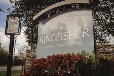 The Kingfisher pub signboard with foliage in daylight.