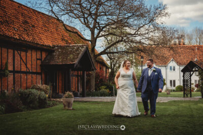 Couple walking in garden at traditional British wedding at Kingfisher Tithe Barn Wedding Venue Bedford..