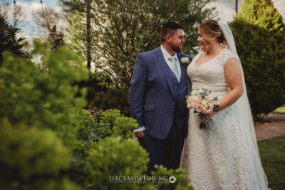 Wedding couple with bouquet in garden setting.