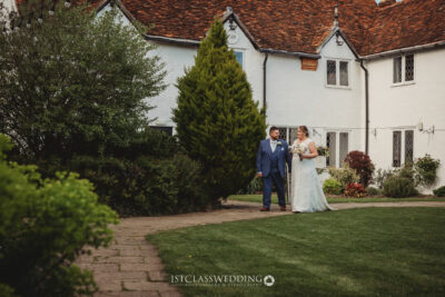 Bride and groom outside historic white cottage.
