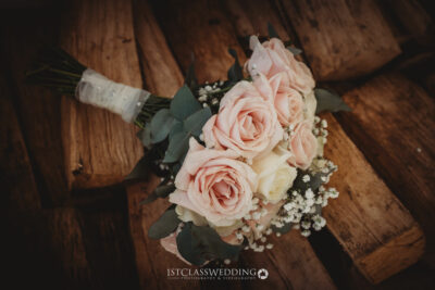 Bridal bouquet with pink roses on wooden background.