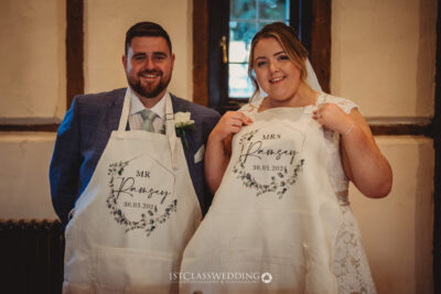 Bride and groom holding personalized wedding aprons.