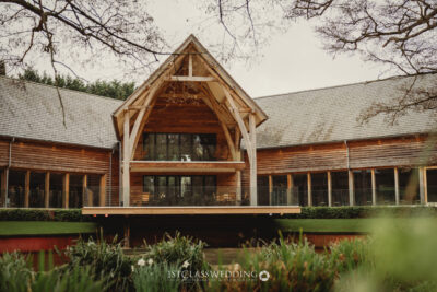 Wooden wedding venue with glass facade amidst trees.
