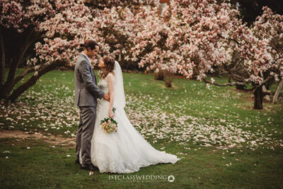 Couple wedding photo under blossoming magnolia trees.