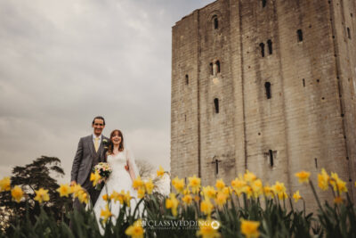 Bride and groom with daffodils by castle.