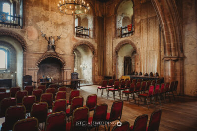 Historic medieval hall with ornate fireplace and chandeliers.