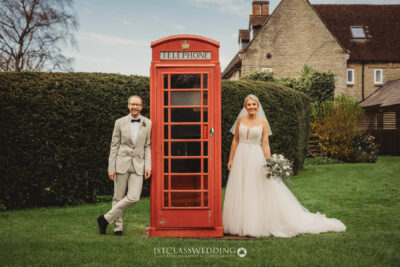 Wedding couple posing by red telephone box.