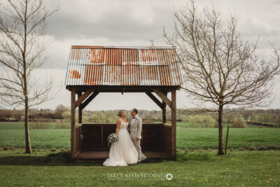 Couple embracing in rustic gazebo, countryside wedding setting at Huntsmill Farm
